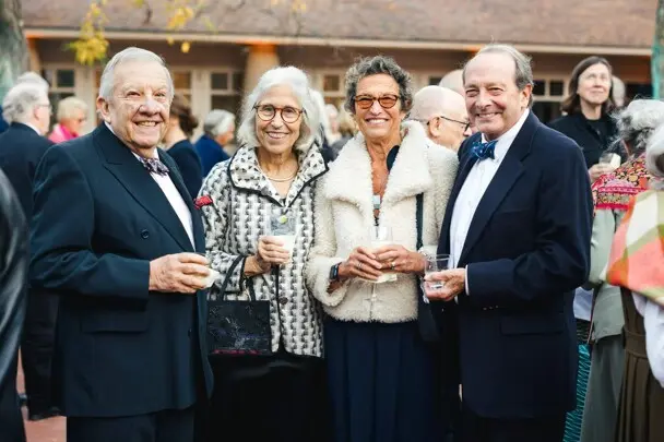 Trustees and gala guest stand with cocktails in Museum courtyard.