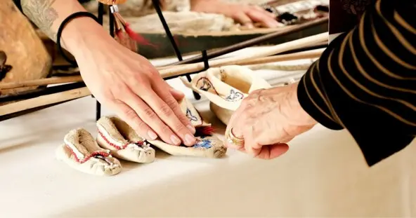 Museum educator teaches guest about regalia.