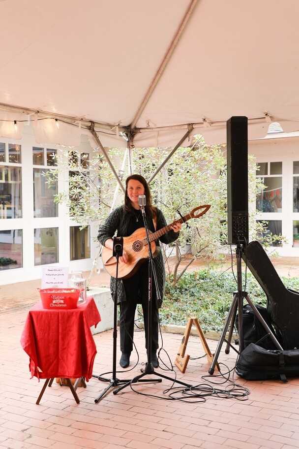 Musician Abby Vail plays guitar and sings in tented courtyard.