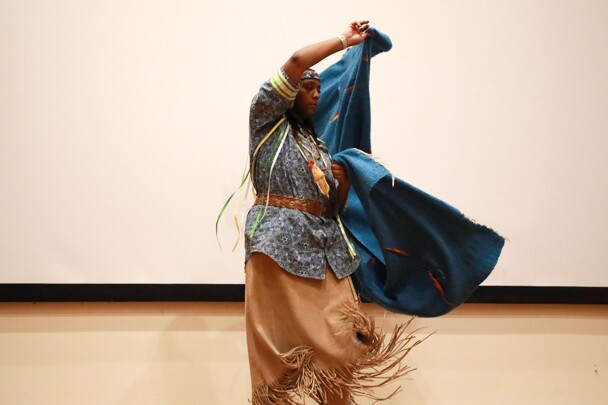 A member of Standing Quiver Singers demonstrates the blanket dance on stage.