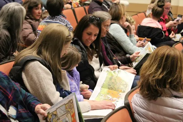 A family in the Lynn Theater read a Jan Brett book.
