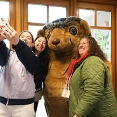 Three guests take a selfie with Hedgie.