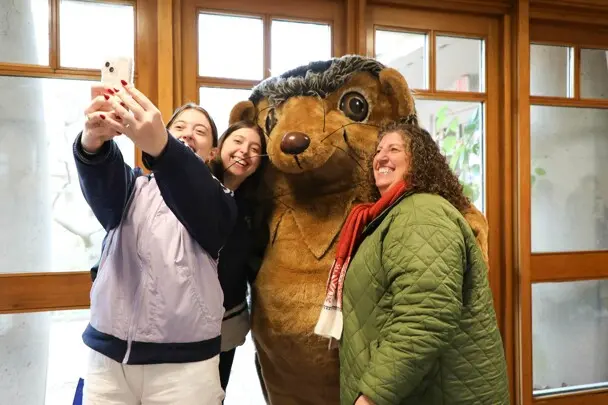Three guests take a selfie with Hedgie.