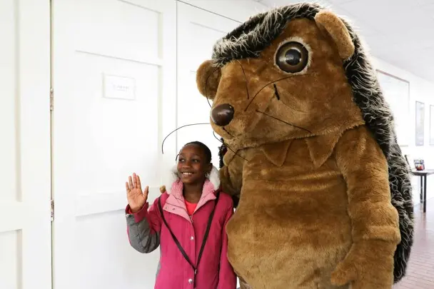 Hedgie poses for a photo with a young guest.