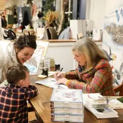 Jan Brett signs a book for a mother and child.