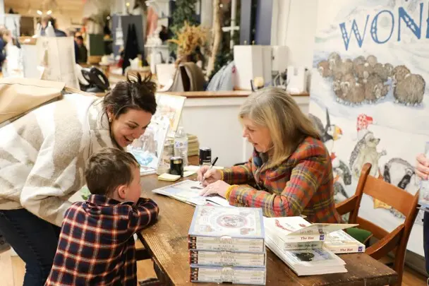 Jan Brett signs a book for a mother and child.