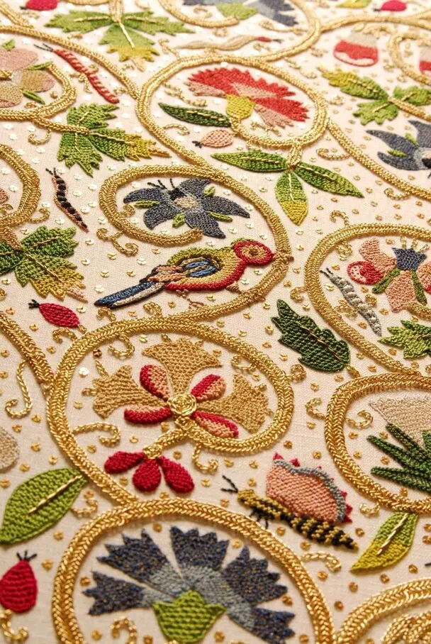 Colorful embroidery of birds, bees, and flowers on a white background.