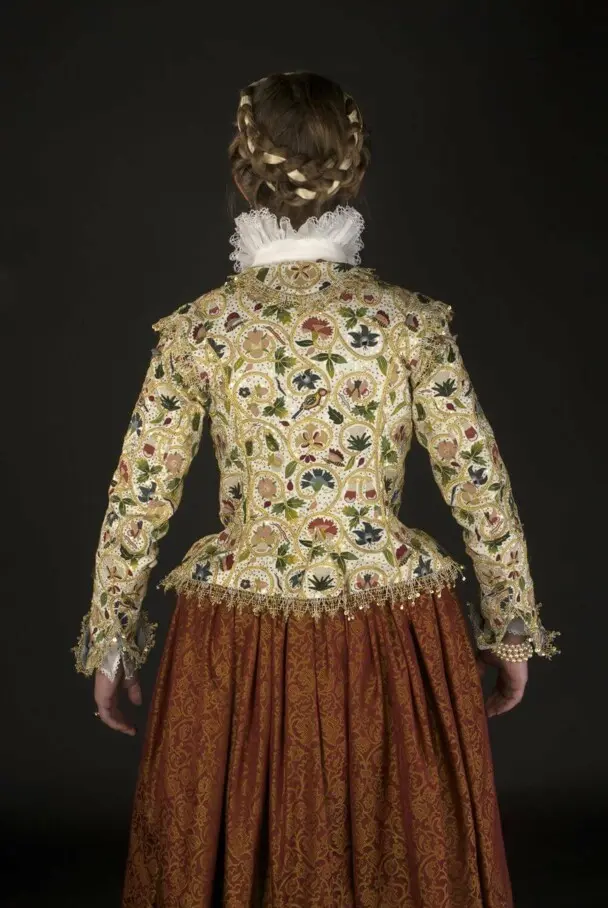 A woman models the back of the Plimoth Jacket and 17th century clothing.