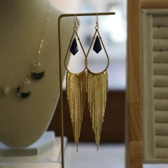Dangle earrings displayed on a table with additional pieces of jewelry.