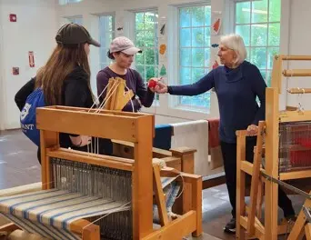 Volunteer hands wool sample to Museum guest.