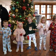 Children stand in front of a decorated Christmas tree in the Museum's lobby.