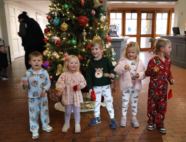 Children stand in front of a decorated Christmas tree in the Museum's lobby.