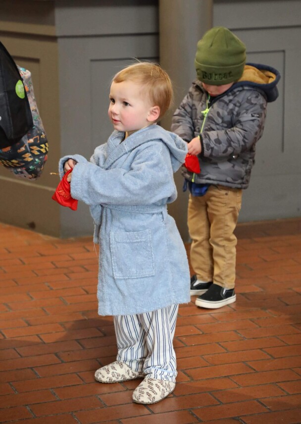 Young boy in pajamas holds a velvet bag containing a magical bell..
