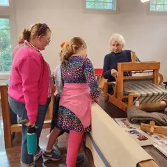 Guests watch a volunteer process wool.