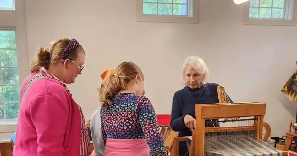 Guests watch a volunteer process wool.
