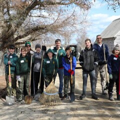 A group of boy scouts stand together holding rakes and shovels in the 17th-Century English Village.