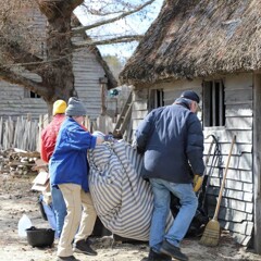 Volunteers work together to carry a mattress inside of a Pilgrim house.