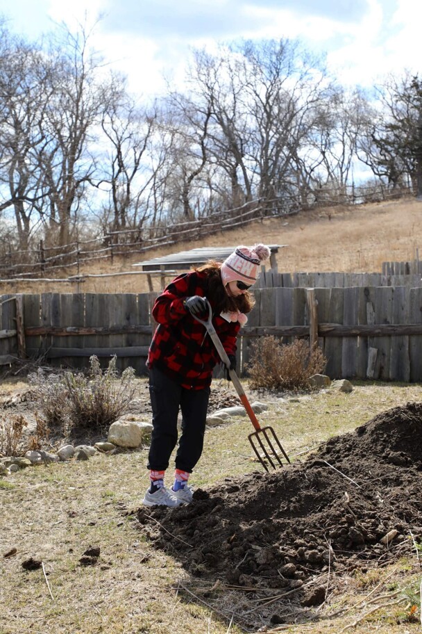 A woman works in the kitchen garden of a Pilgrim house.