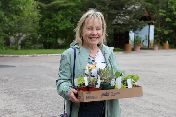 Woman smiles as she holds box of seedlings