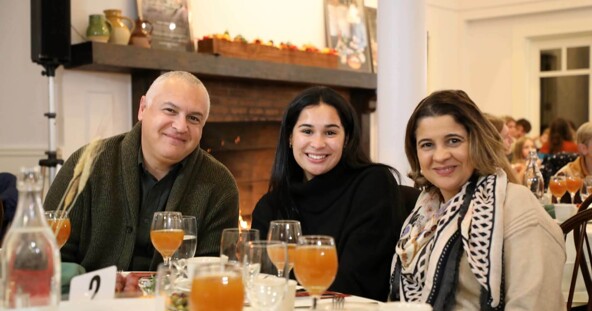 Three guests seated at Thanksgiving table with glasses of apple cider