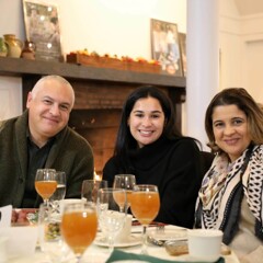 Three guests seated at Thanksgiving table with glasses of apple cider