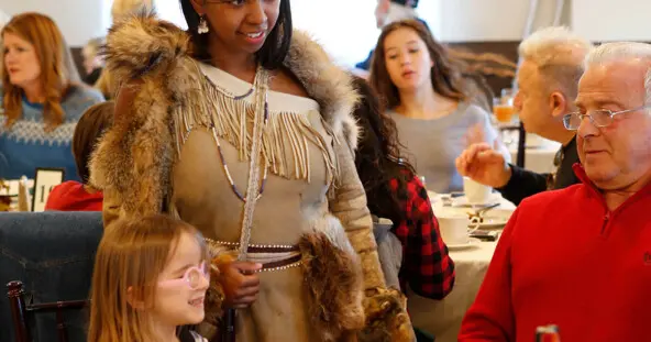 Indigenous Educator in Wampanoag regalia greets Thanksgiving guests