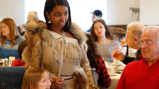 Indigenous Educator in Wampanoag regalia greets Thanksgiving guests