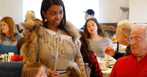 Indigenous Educator in Wampanoag regalia greets Thanksgiving guests