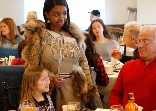 Indigenous Educator in Wampanoag regalia greets Thanksgiving guests