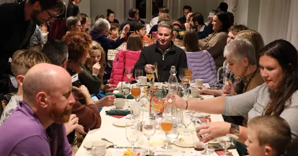 Waiters serve dozens of guests seated at Thanksgiving tables.