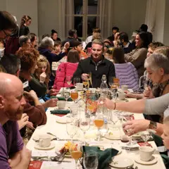 Waiters serve dozens of guests seated at Thanksgiving tables.