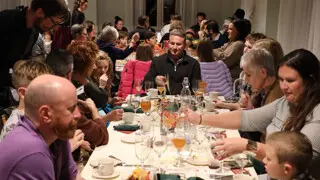 Waiters serve dozens of guests seated at Thanksgiving tables.