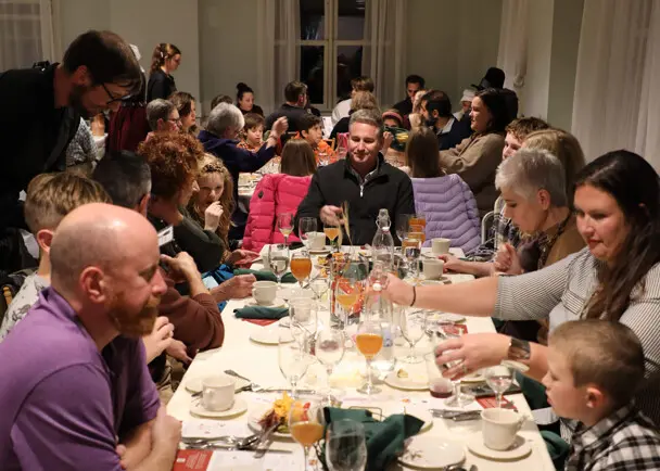 Waiters serve dozens of guests seated at Thanksgiving tables.