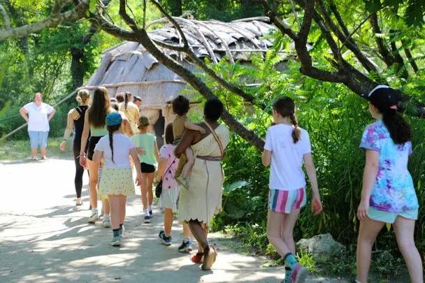 Line of guests and Museum Educators enter the wetu on the Historic Patuxet Homesite