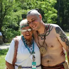Two educators greet and hug each other on the Historic Patuxet Homesite
