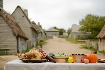 Table set for Thanksgiving in the English village with pilgrim houses in the background.