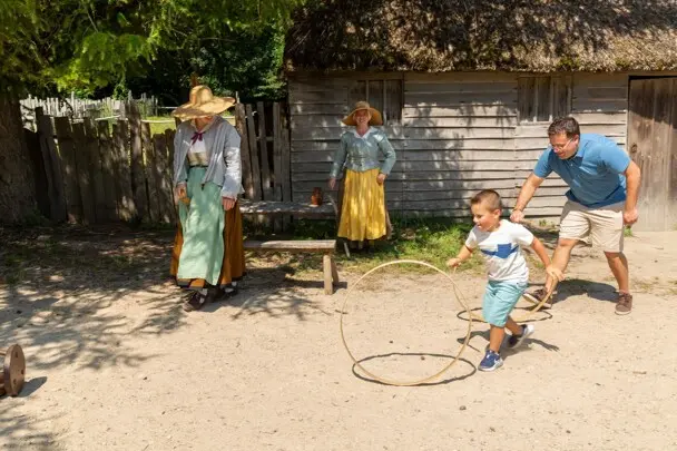 Father and son spin hoops with Pilgrims in English Village