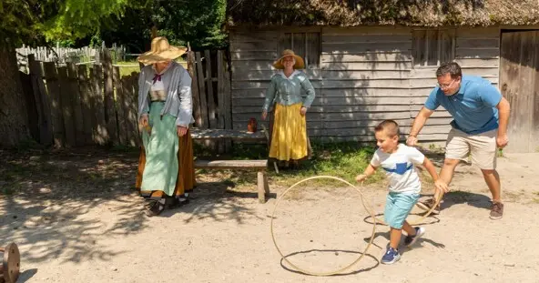 Father and son spin hoops with Pilgrims in English Village