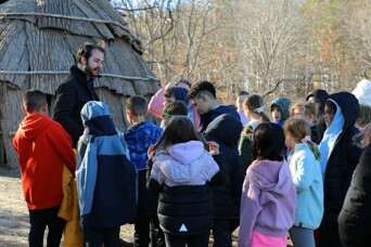 Museum guide provides tour of the Historic Patuxet Homesite to a group of children on a field trip.