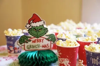 Festive cups of popcorn surround a Grinch holiday table decoration.