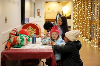 A mother helps children write letters to Santa.