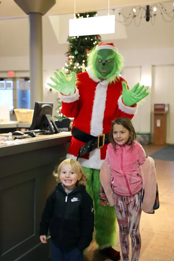 Grinch poses with two children at Plimoth Patuxet during the Matinee event.