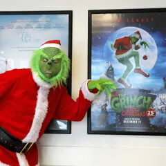 The Grinch poses with his own framed movie poster.