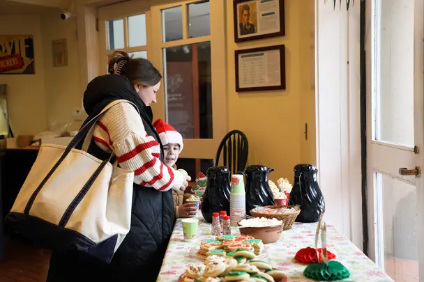 Mother and child peruse holiday cookies, hot cocoa, and other treats.