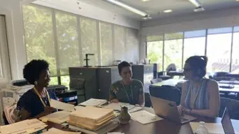 three women at a table in museum collections