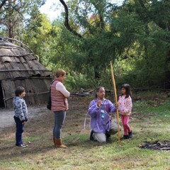 An Educator on the Historic Patuxet Homesite teaches young guests archery beside the winter wetu.