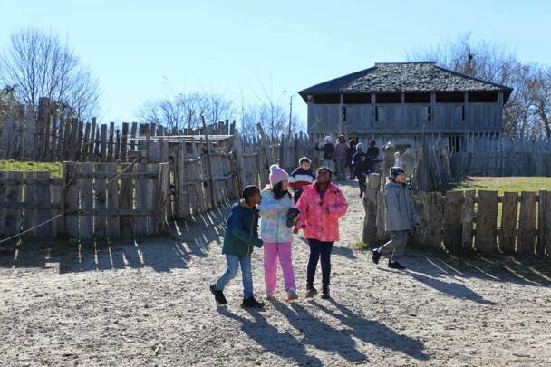 Late elementary aged students stream into the 17th-Century English Village in the late fall.