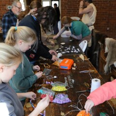 Crowded craft table in the Craft center with participants of all ages.