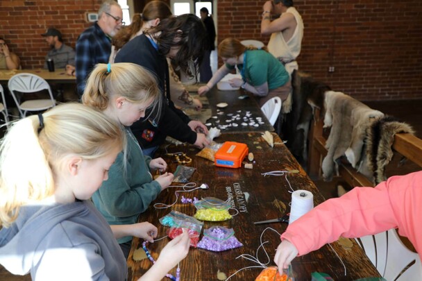 Crowded craft table in the Craft center with participants of all ages.