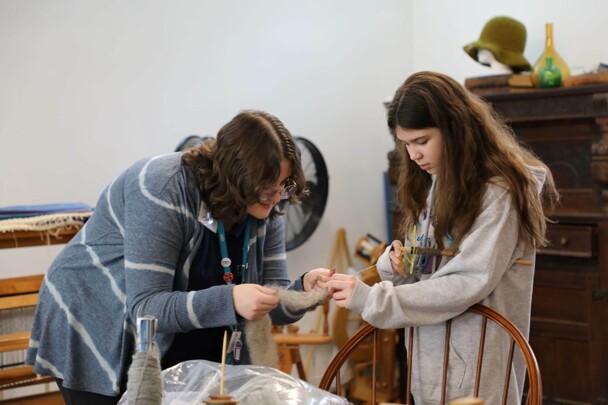 An Educator and young learner examine wool at the Craft Center.